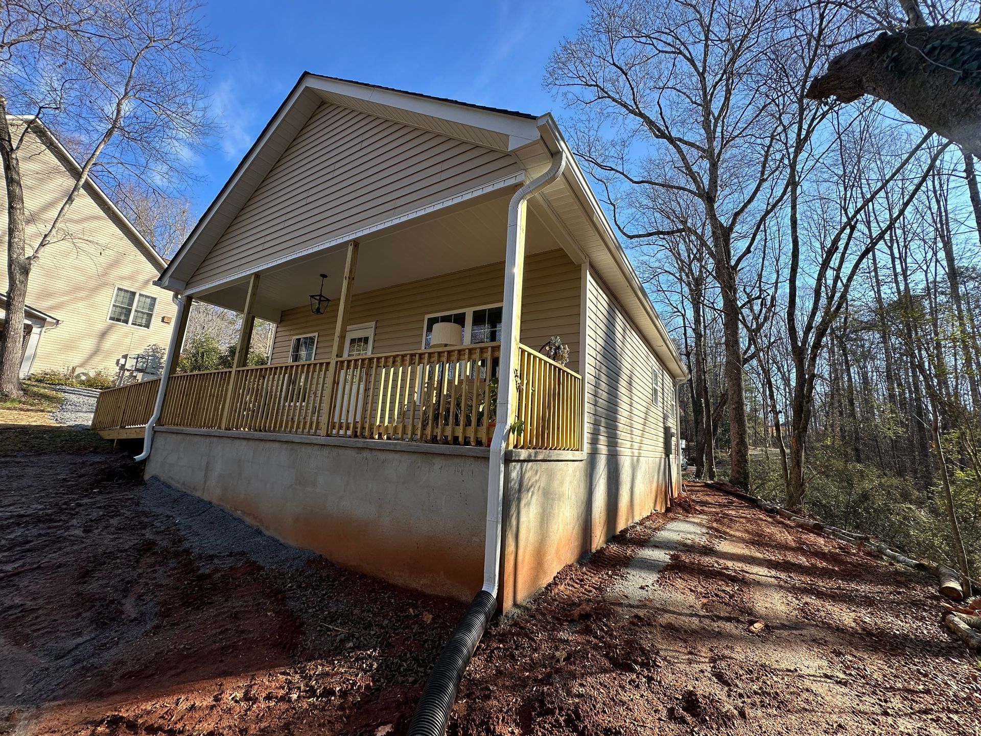 Outdoor shot of the front of a tan house with a wooden porch fence