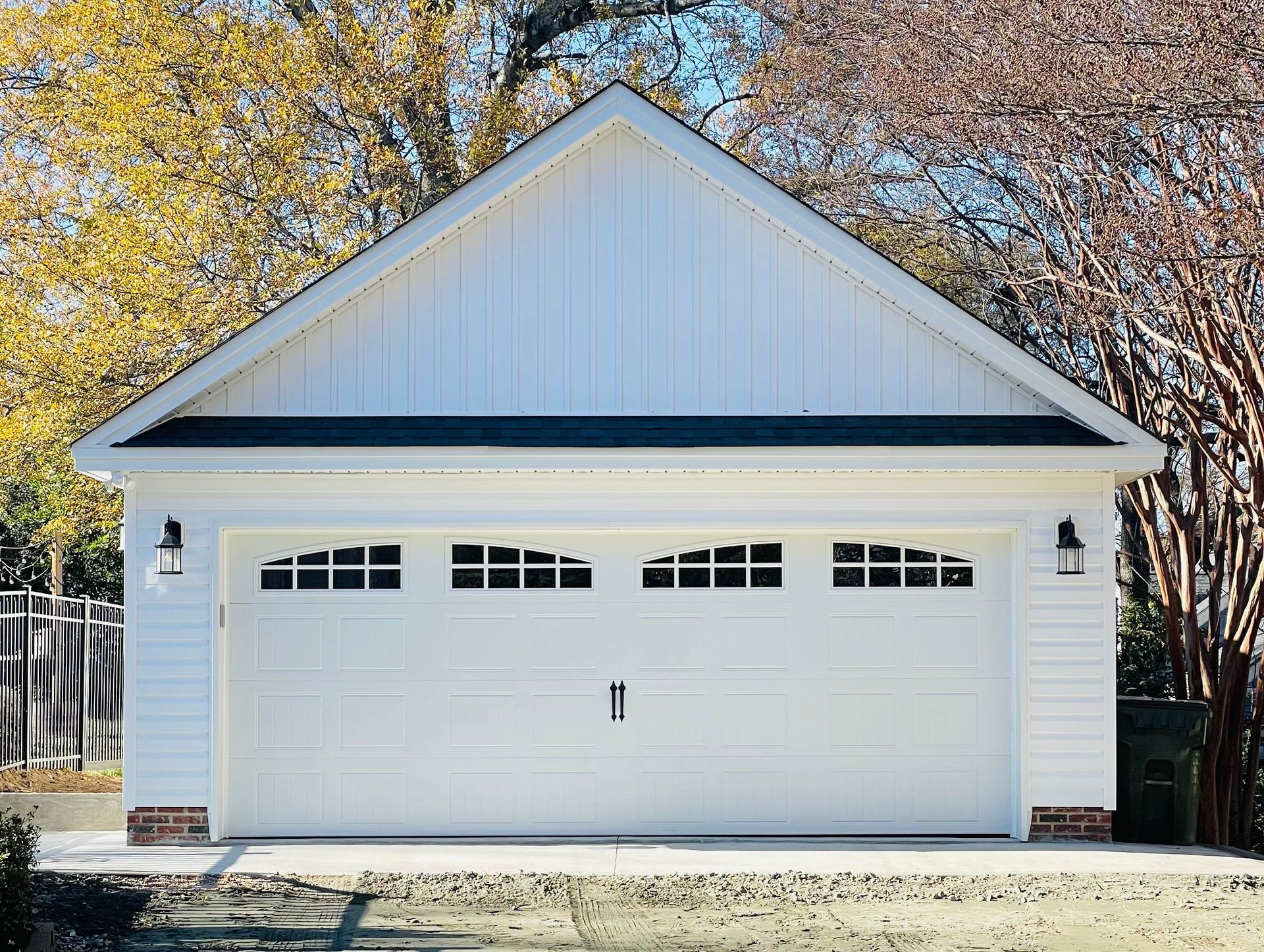 White garage with arched windows, gabled roof, and black light fixtures.