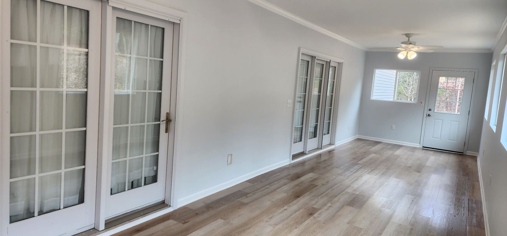 Empty room with wooden floors, light blue walls, and French doors.