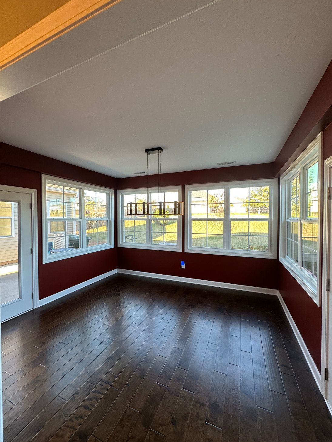An empty living room with hardwood floors and red walls.