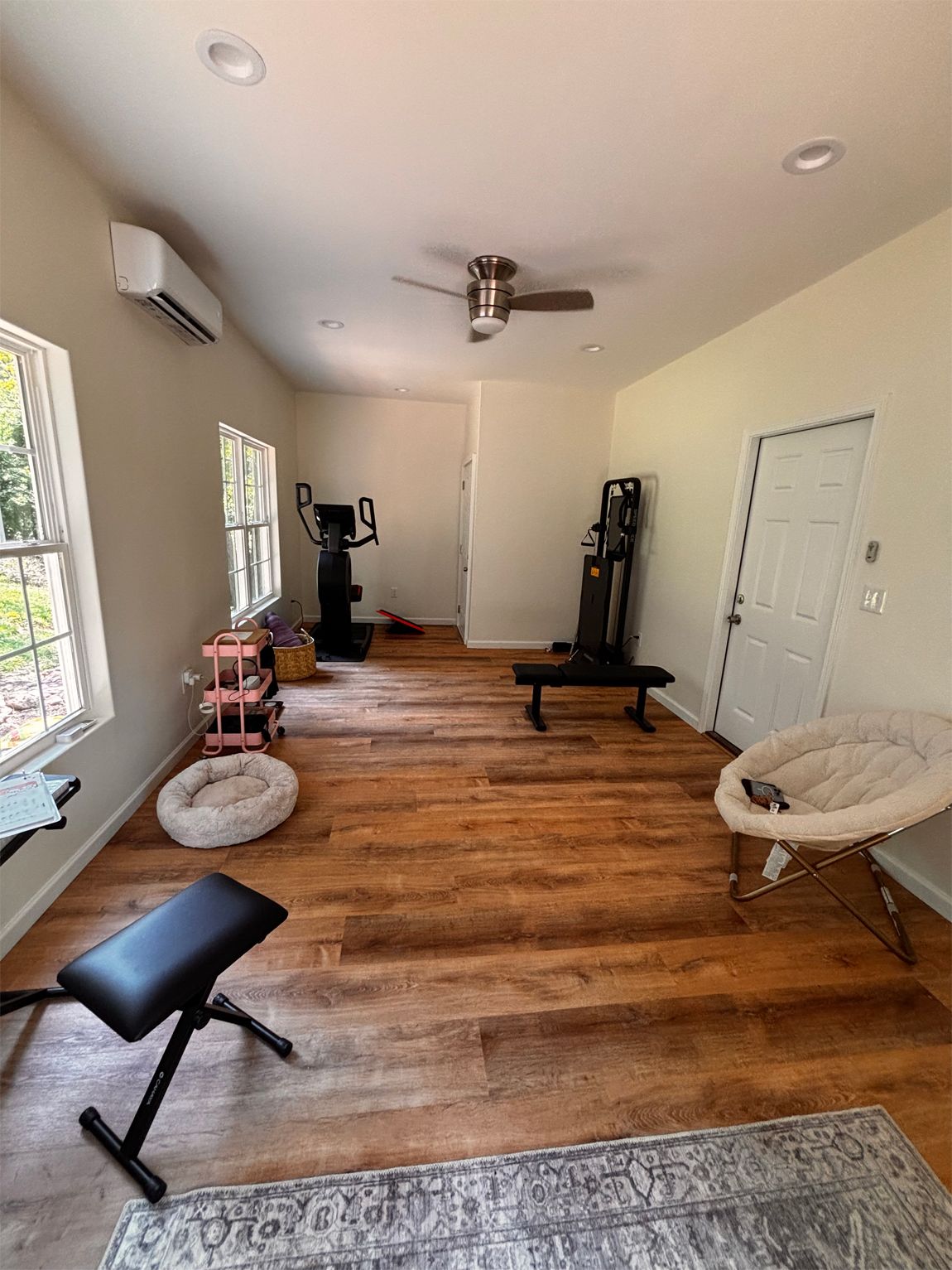 Home gym with exercise equipment, wood floor, white walls, and a ceiling fan.