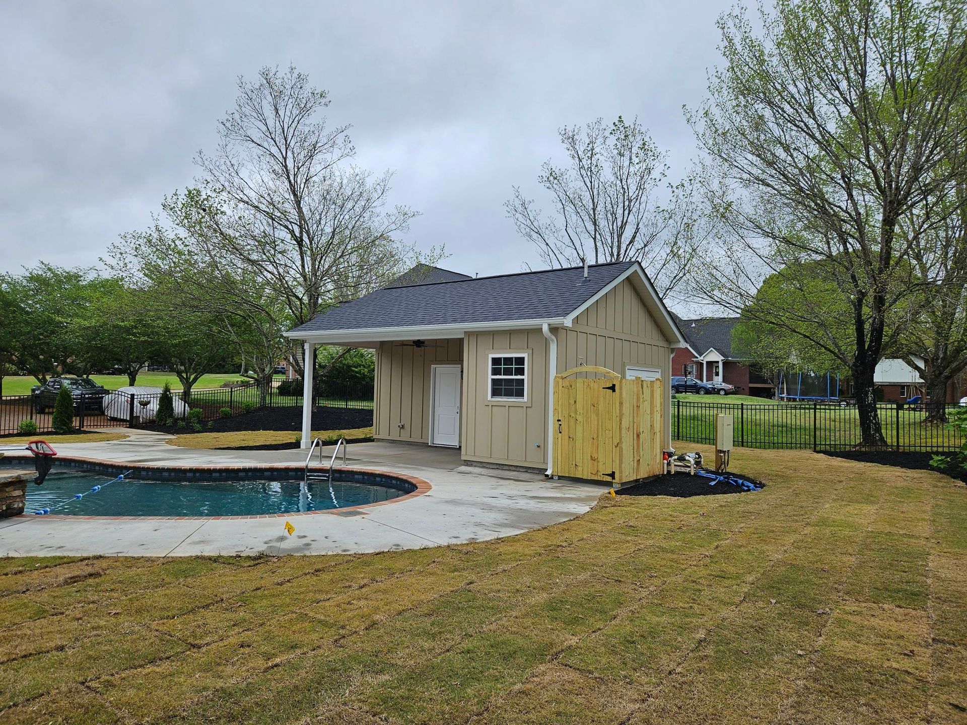 A shed is sitting next to a pool in a backyard.