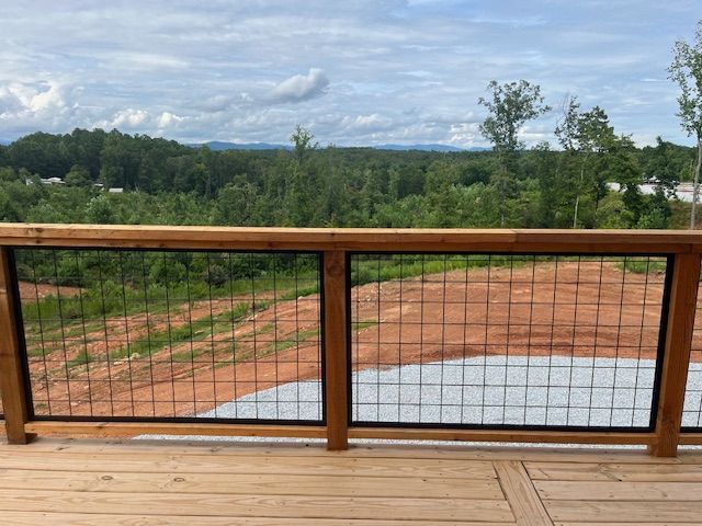 A wooden deck with a metal fence and a view of a forest.