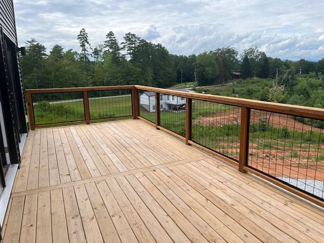 A wooden deck with a metal railing and a view of a field.