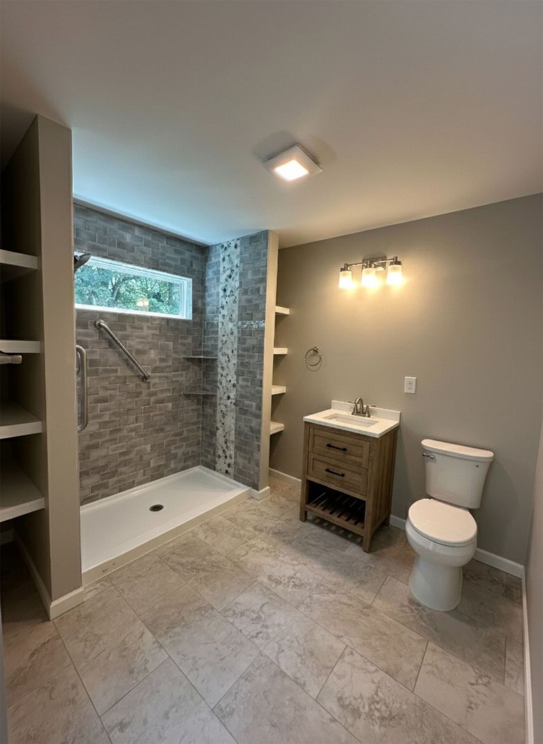 Bathroom with tiled shower, vanity, toilet, and built-in shelves; neutral colors.