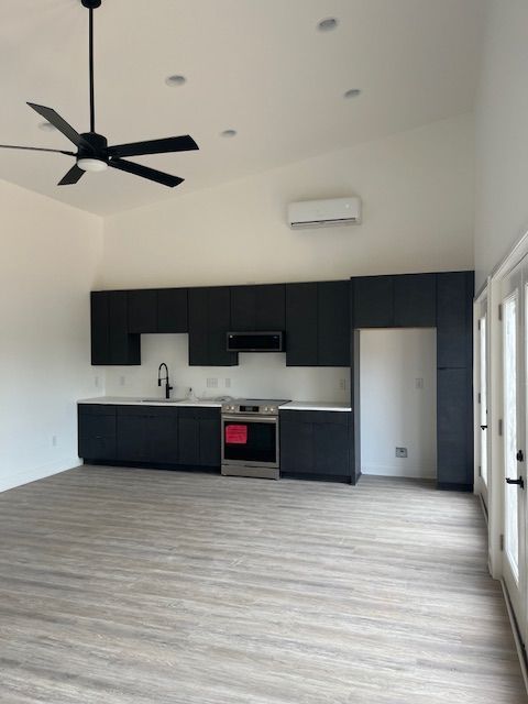 An empty kitchen with black cabinets and a ceiling fan.