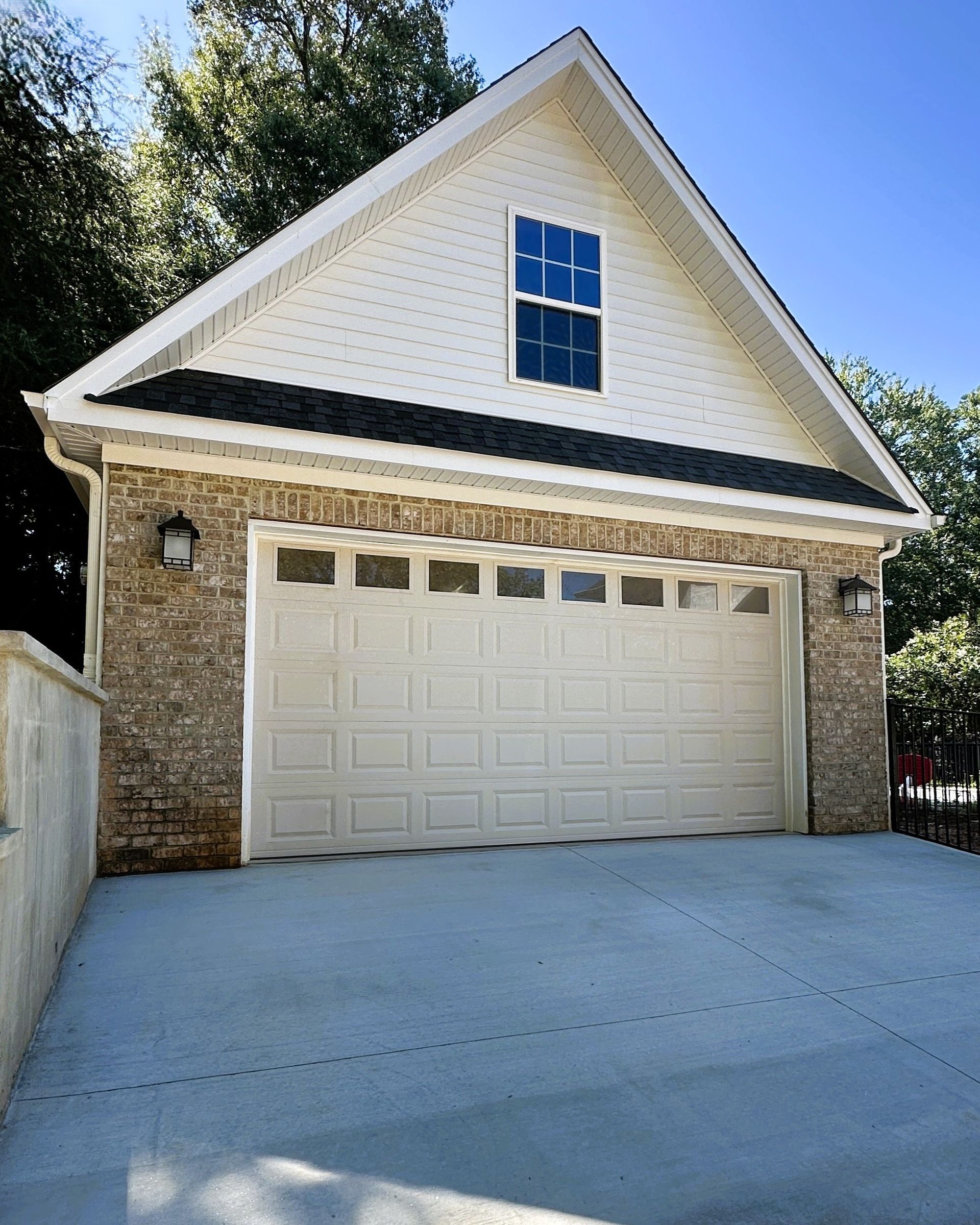 Garage with a white door, brick walls, and a gabled roof.