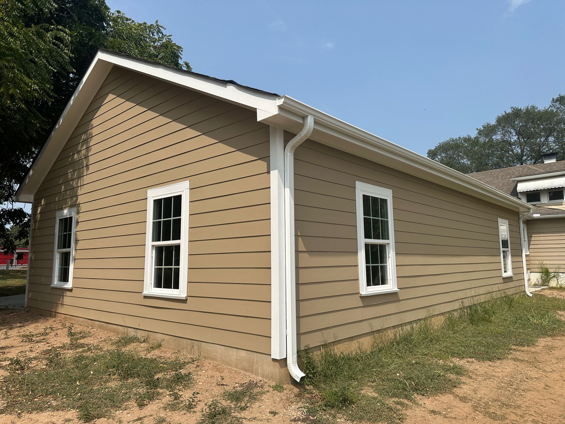 A brown house with white windows and a white gutter