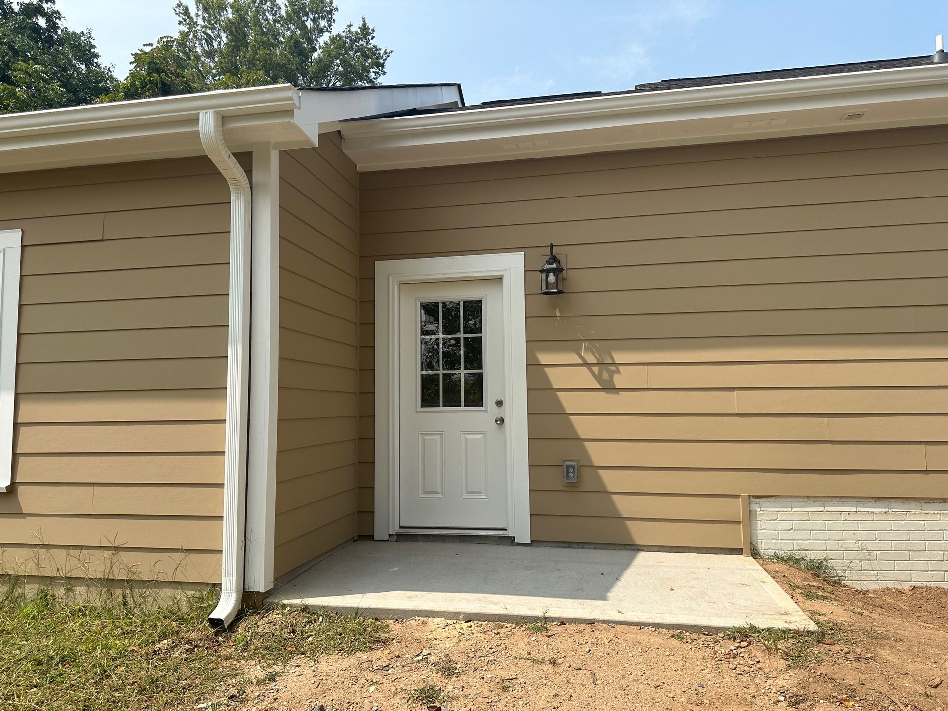 A brown house with a white door and a white gutter