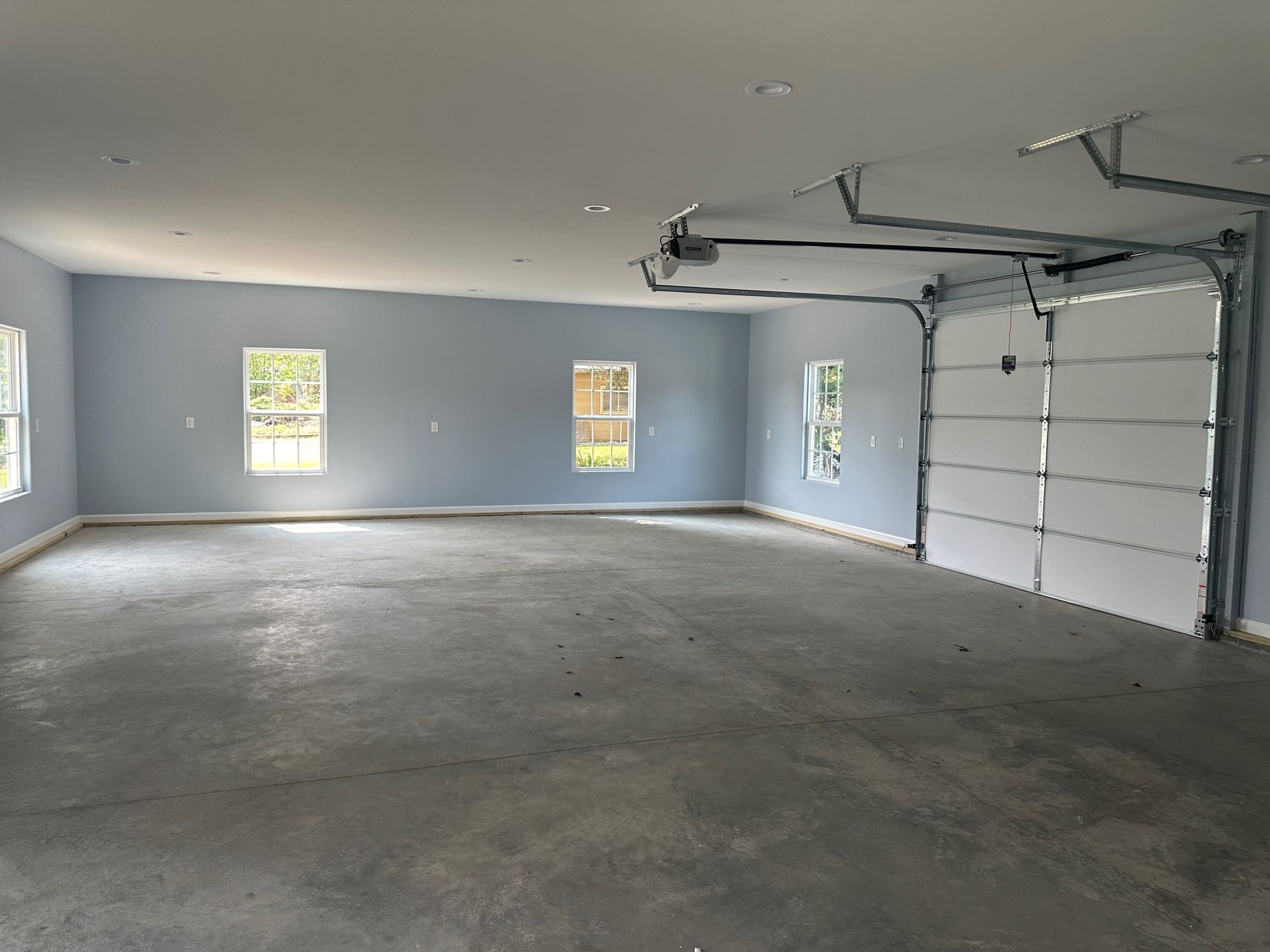 A large empty garage with a white garage door and blue walls.
