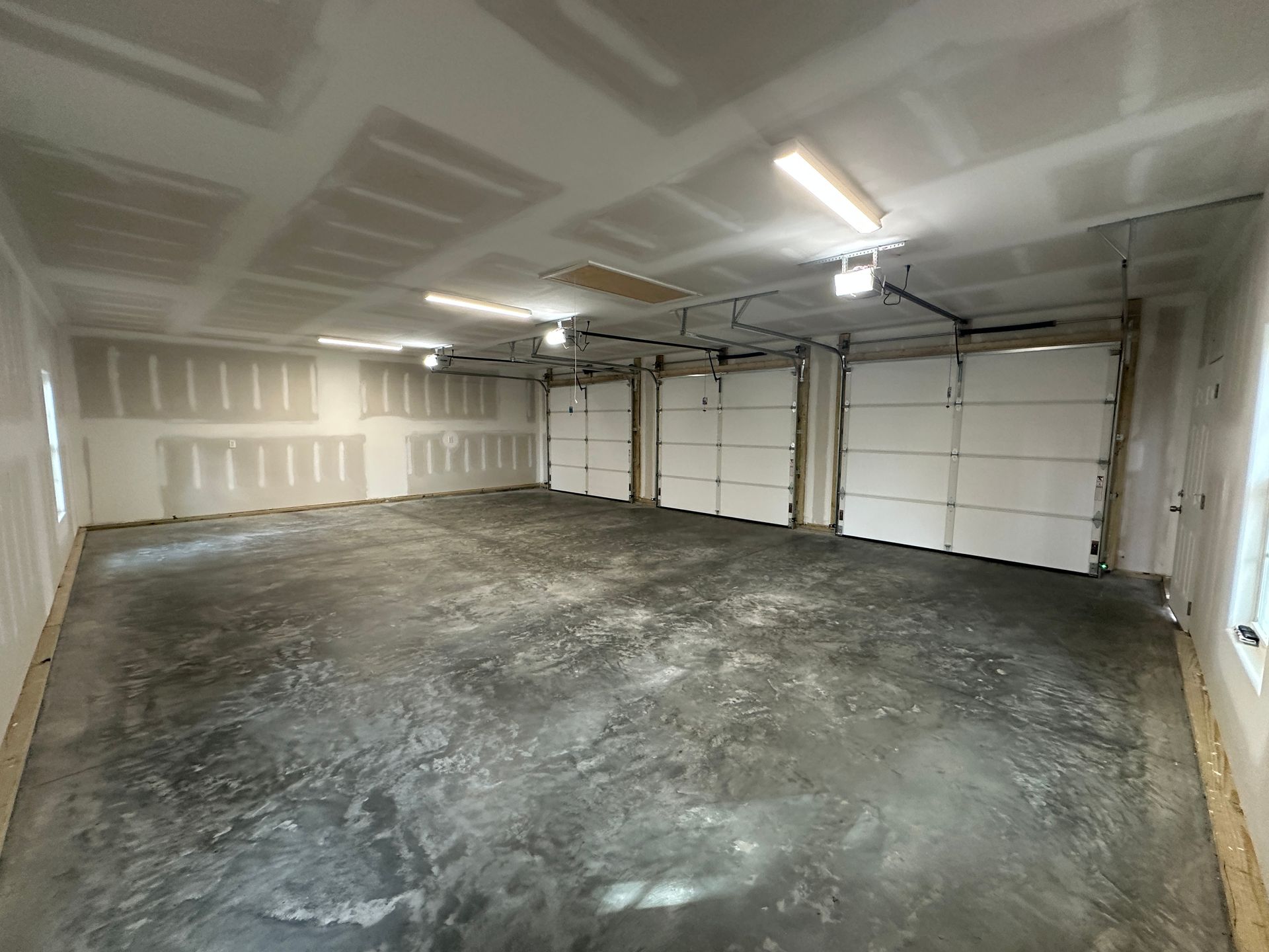 A large empty garage with two garage doors and a concrete floor.