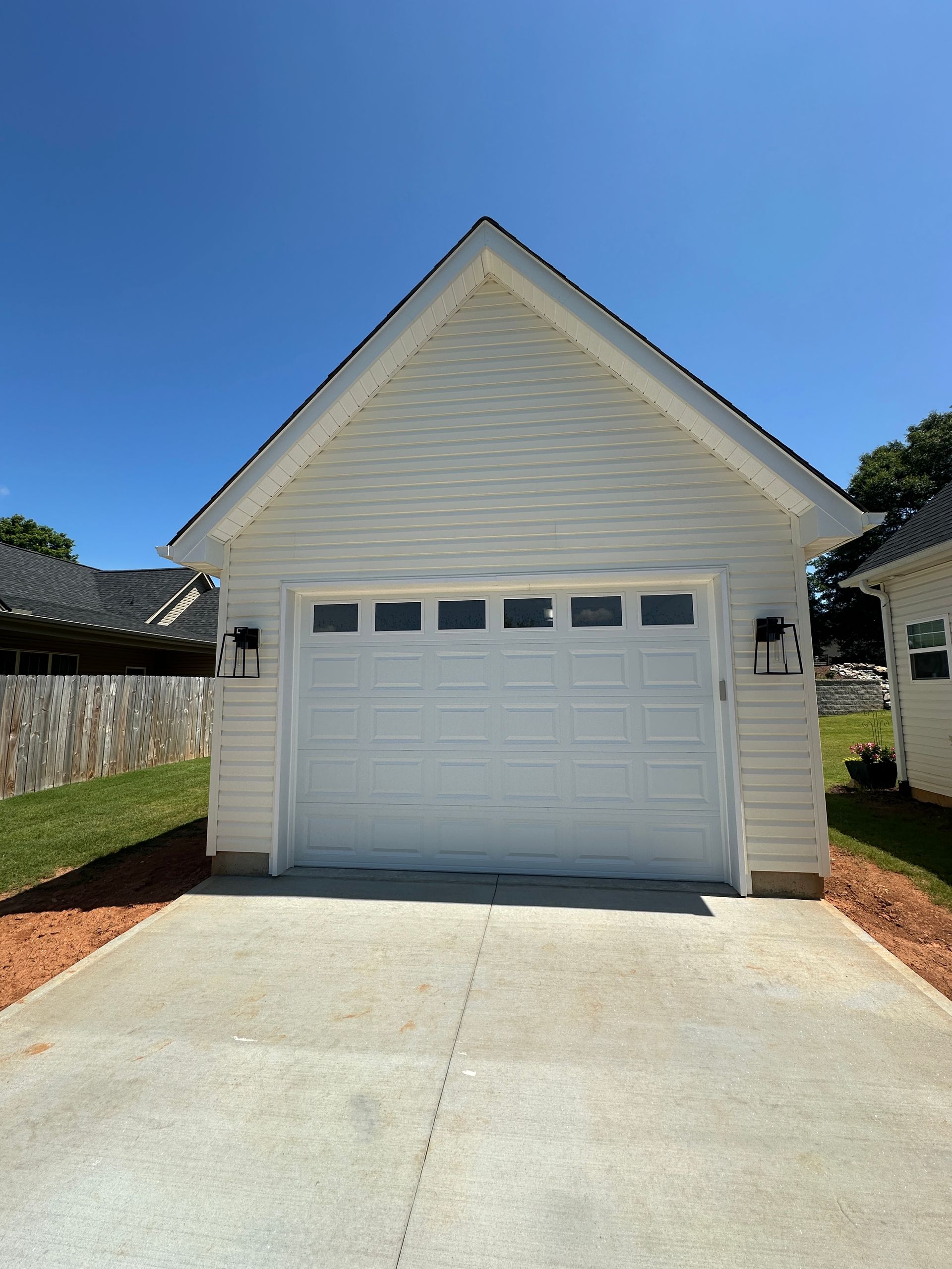 White garage with concrete driveway against a blue sky.