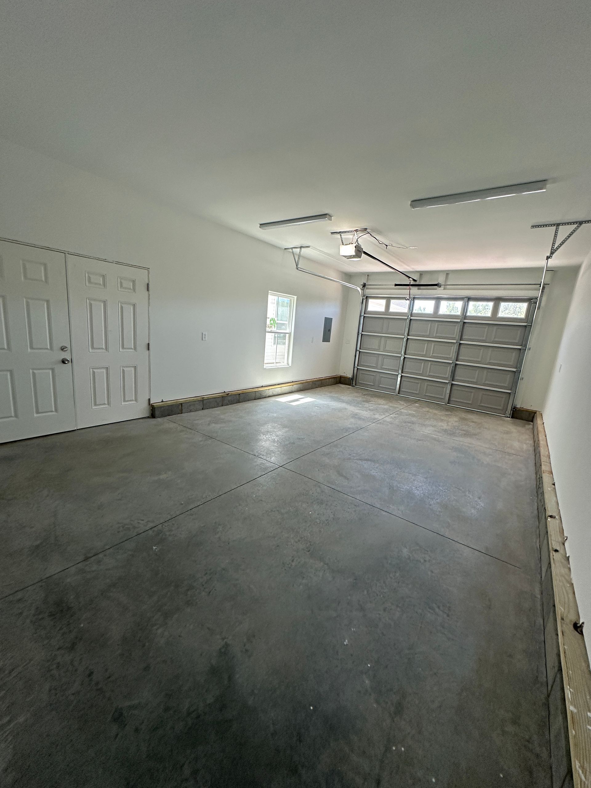 Empty garage with a gray concrete floor, white walls, and a closed garage door.