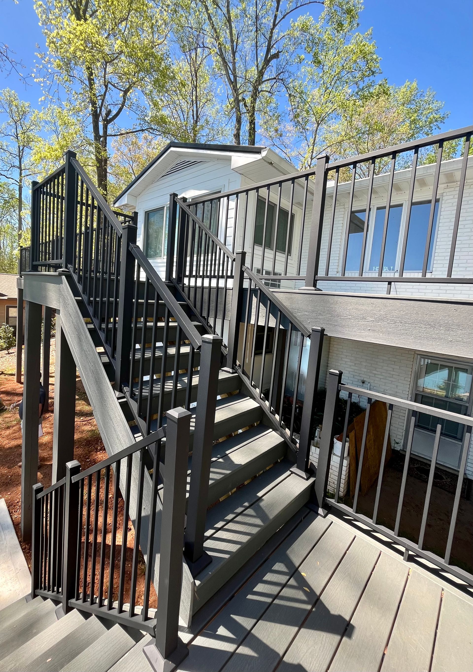A deck with stairs leading up to it and a house in the background.