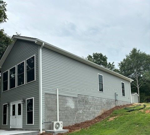 A large house with a lot of windows is sitting on top of a grassy hill