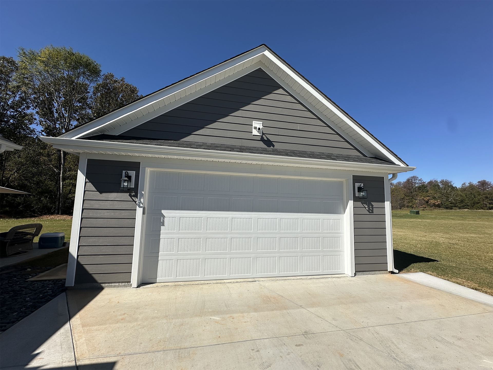 A garage with a gray siding and a white garage door.