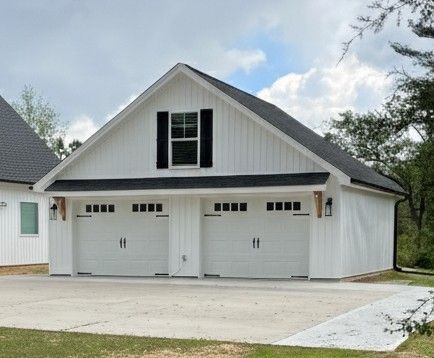 White farmhouse style garage with two doors, black accents, and a small window.