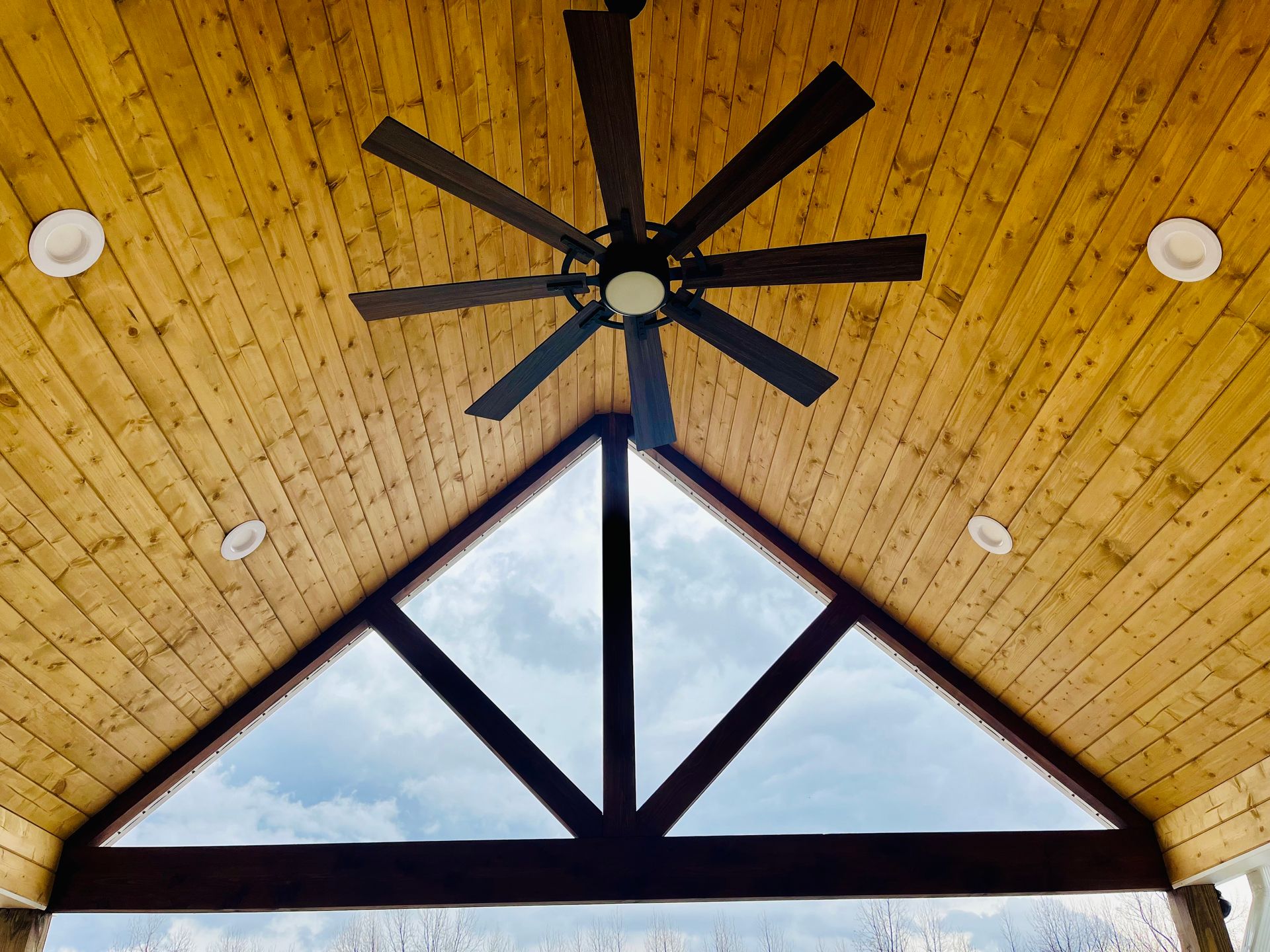 A ceiling fan on a wooden ceiling 