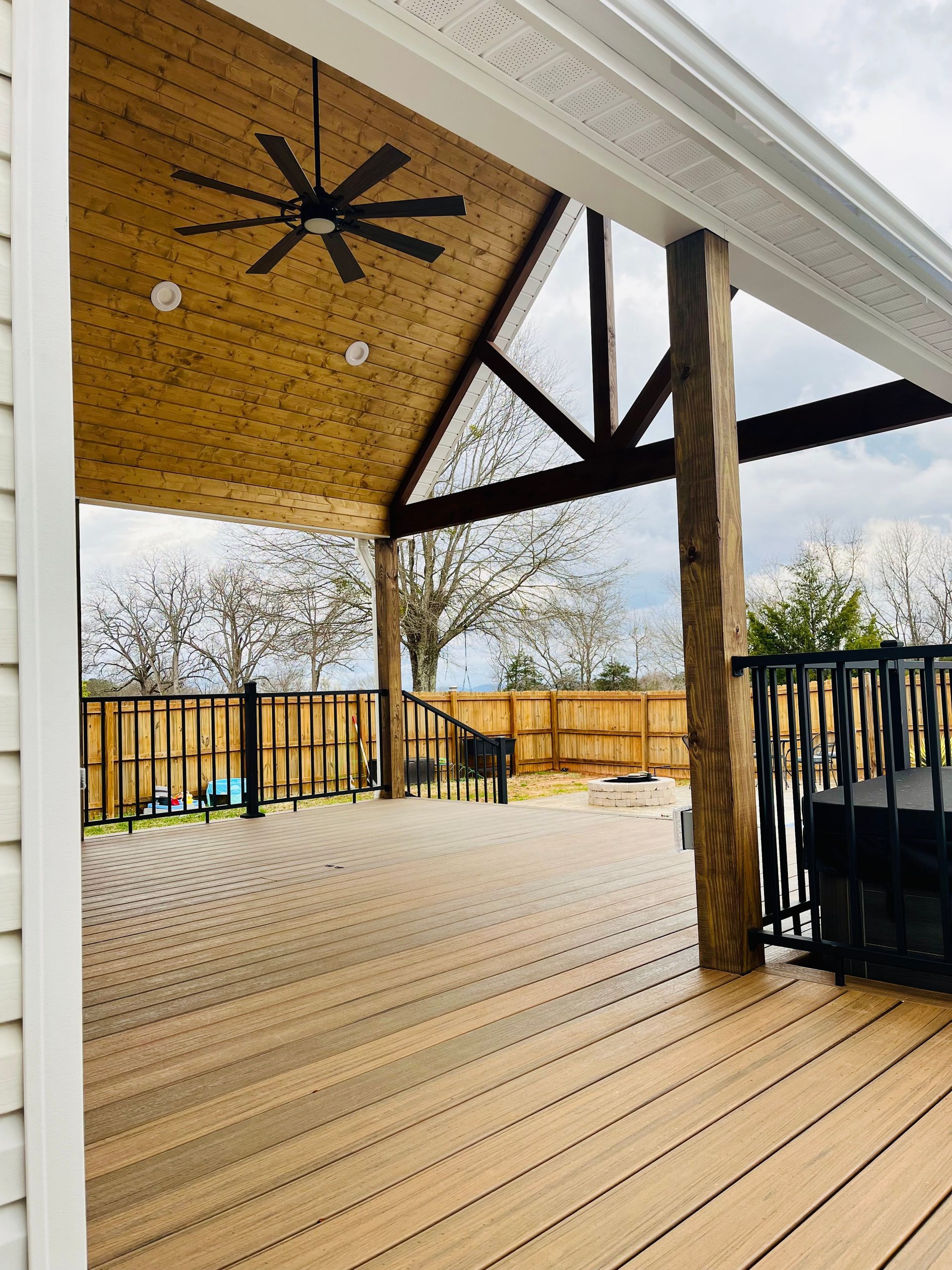 A wooden deck with a ceiling fan on it