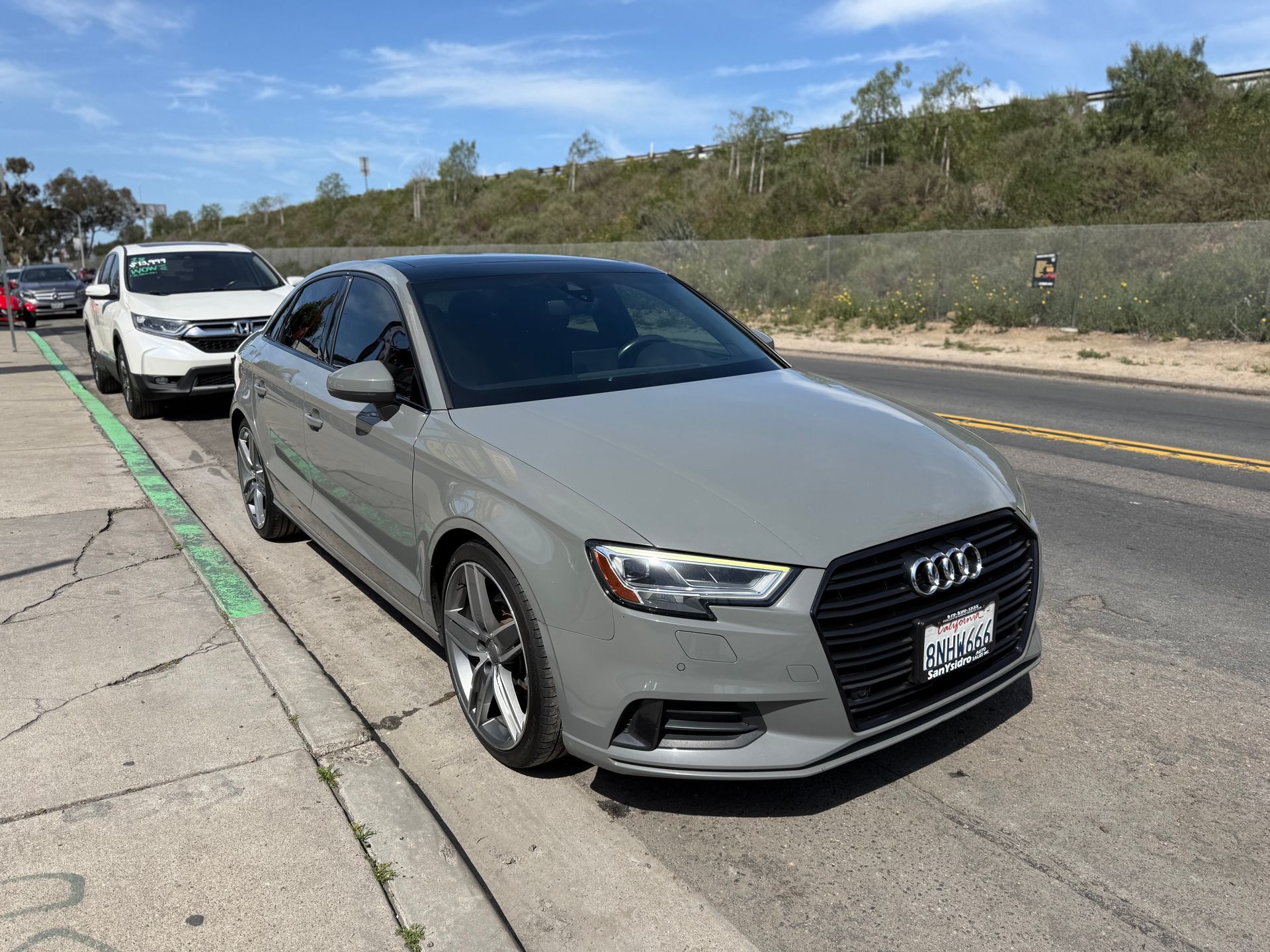 Silver Audi sedan parked along a roadside under a clear sky.