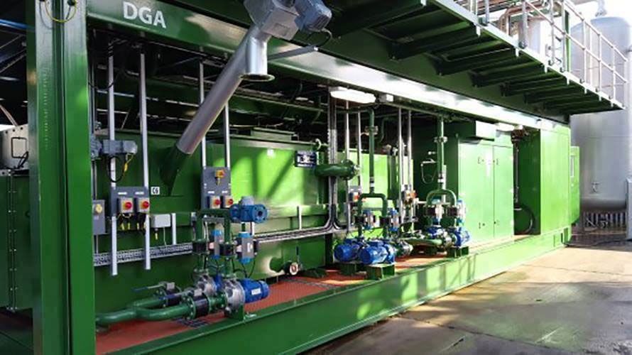 A green and white building with a lot of pipes and pumps.