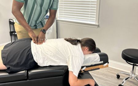 A woman is laying on a bed getting a massage from a man.