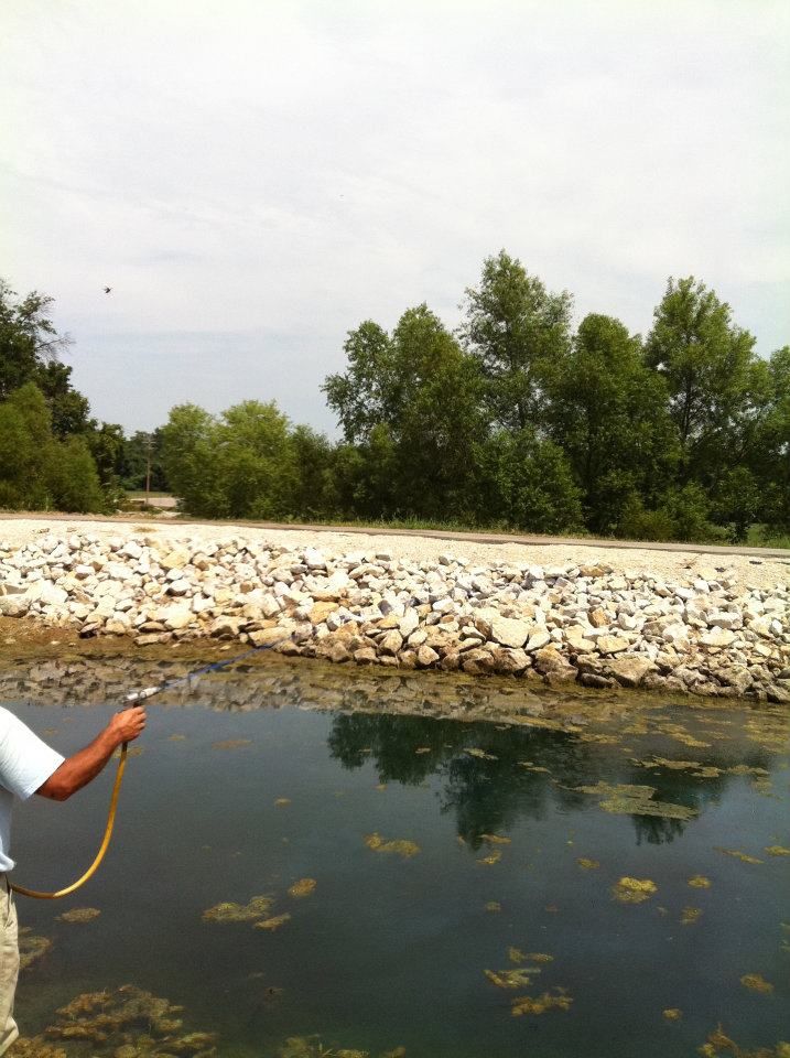 A man is standing next to a body of water holding a rope