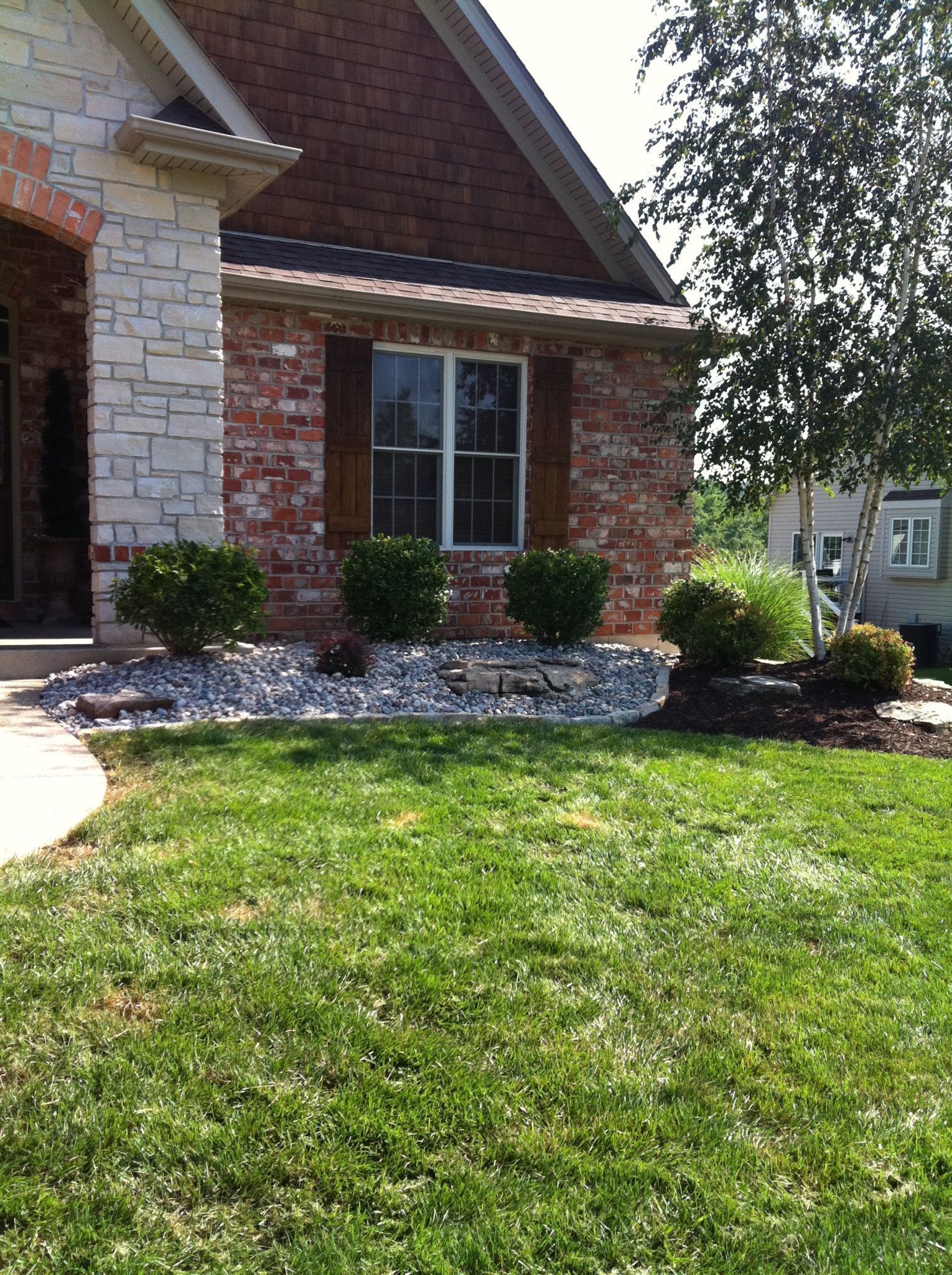 A brick house with a lush green lawn in front of it