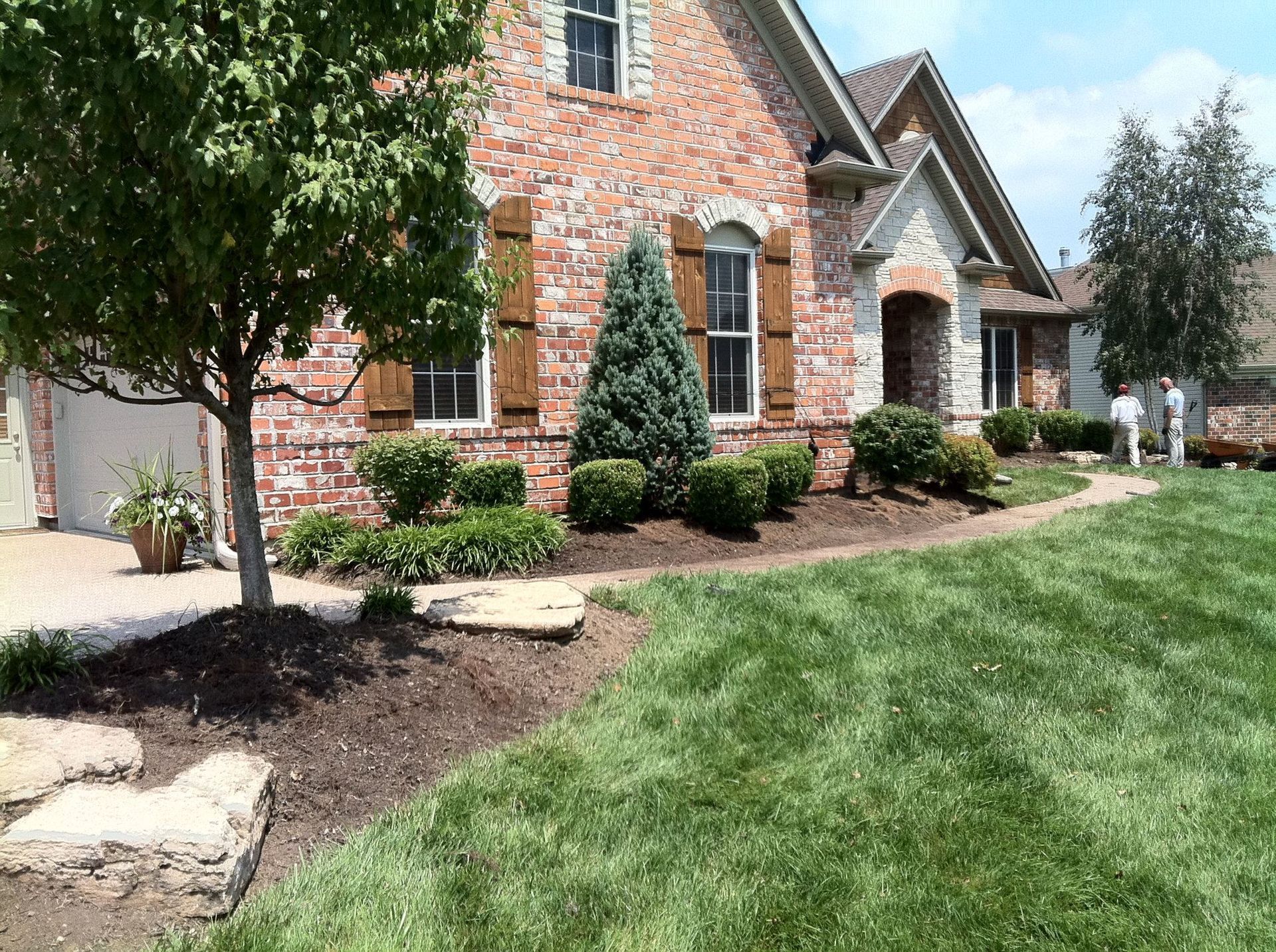 A large brick house with a lush green lawn in front of it.