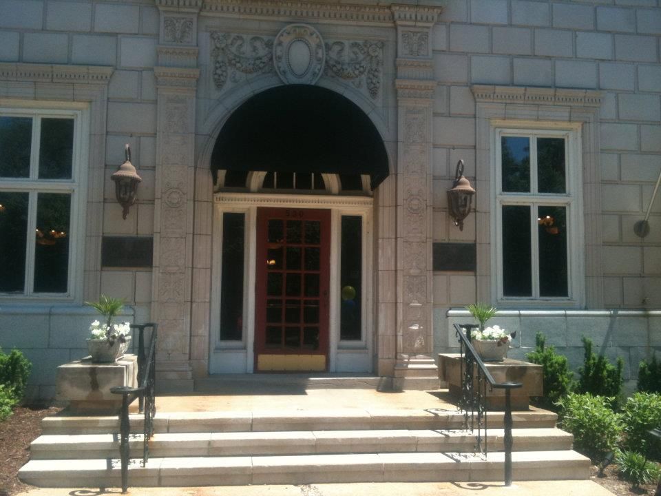 A brick building with a red door and stairs