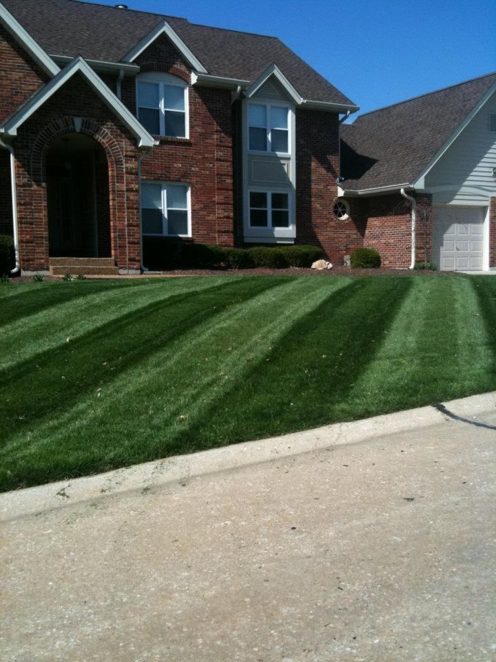 A brick house with a lush green lawn in front of it