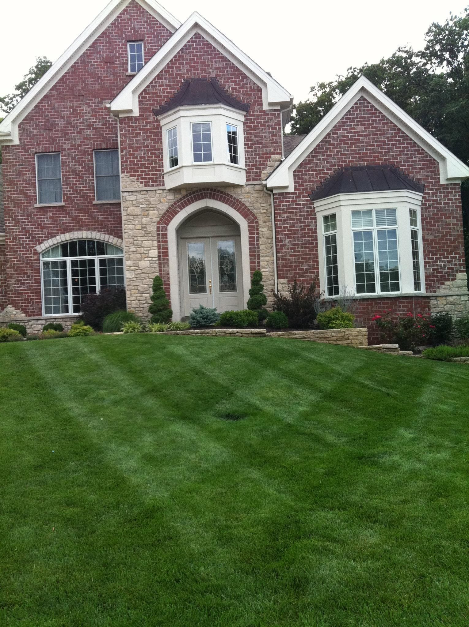 A large brick house with a lush green lawn in front of it