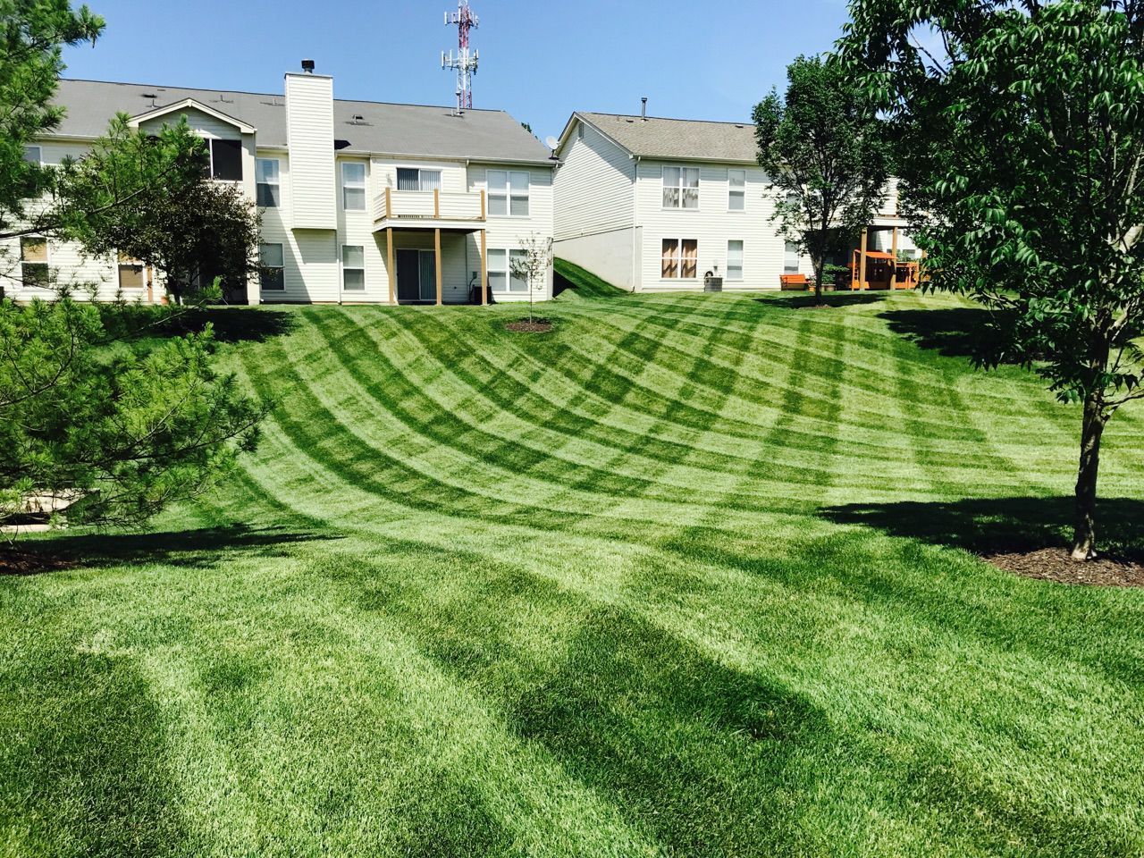 A lush green lawn is being mowed in front of a house.