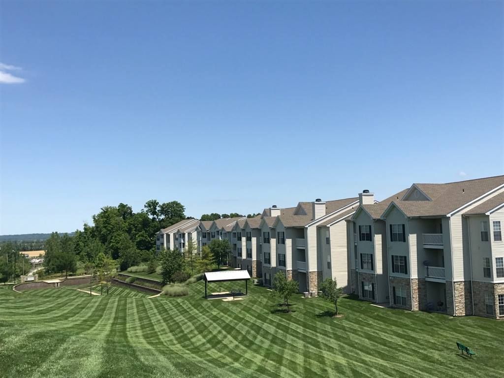A large apartment building with a lush green lawn in front of it.