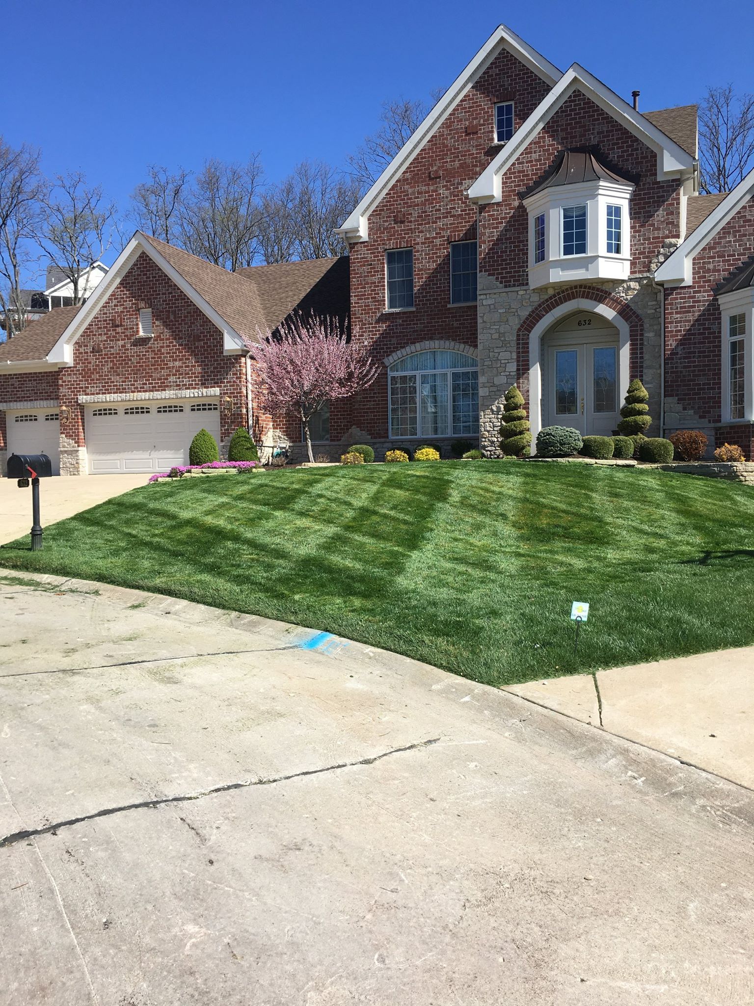 A large brick house with a lush green lawn in front of it.
