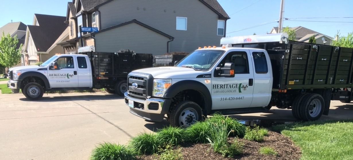 Two dump trucks are parked in front of a house.