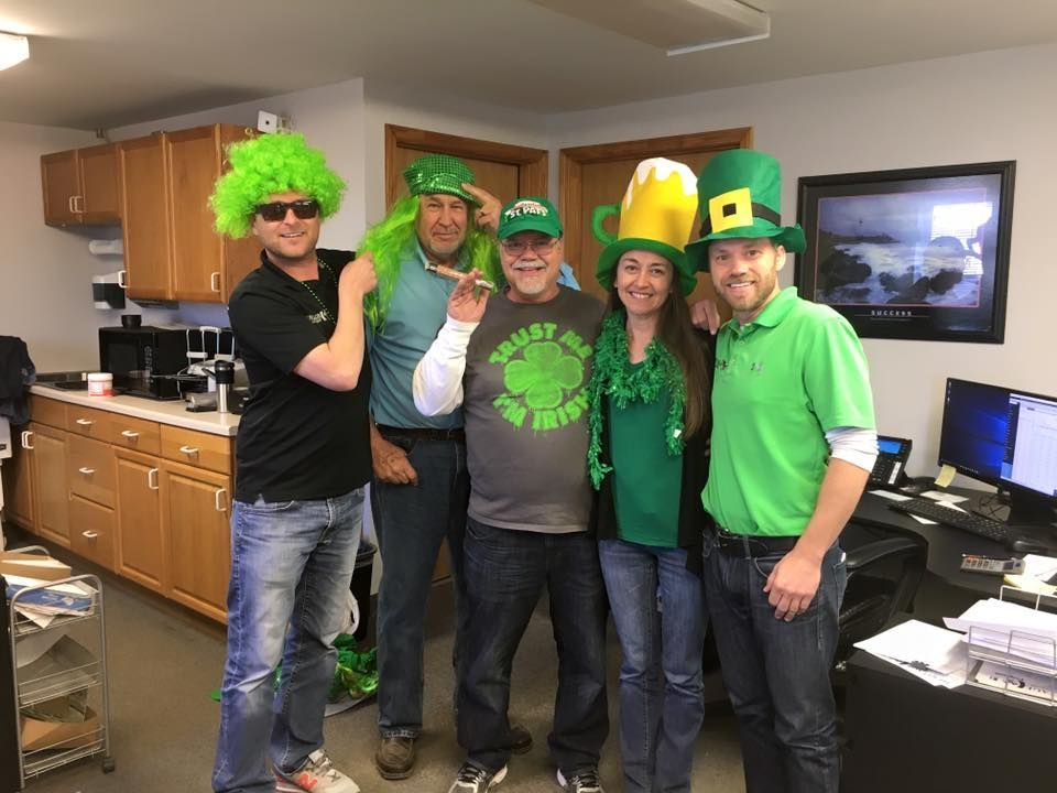 A group of people wearing green hats and wigs are posing for a picture.