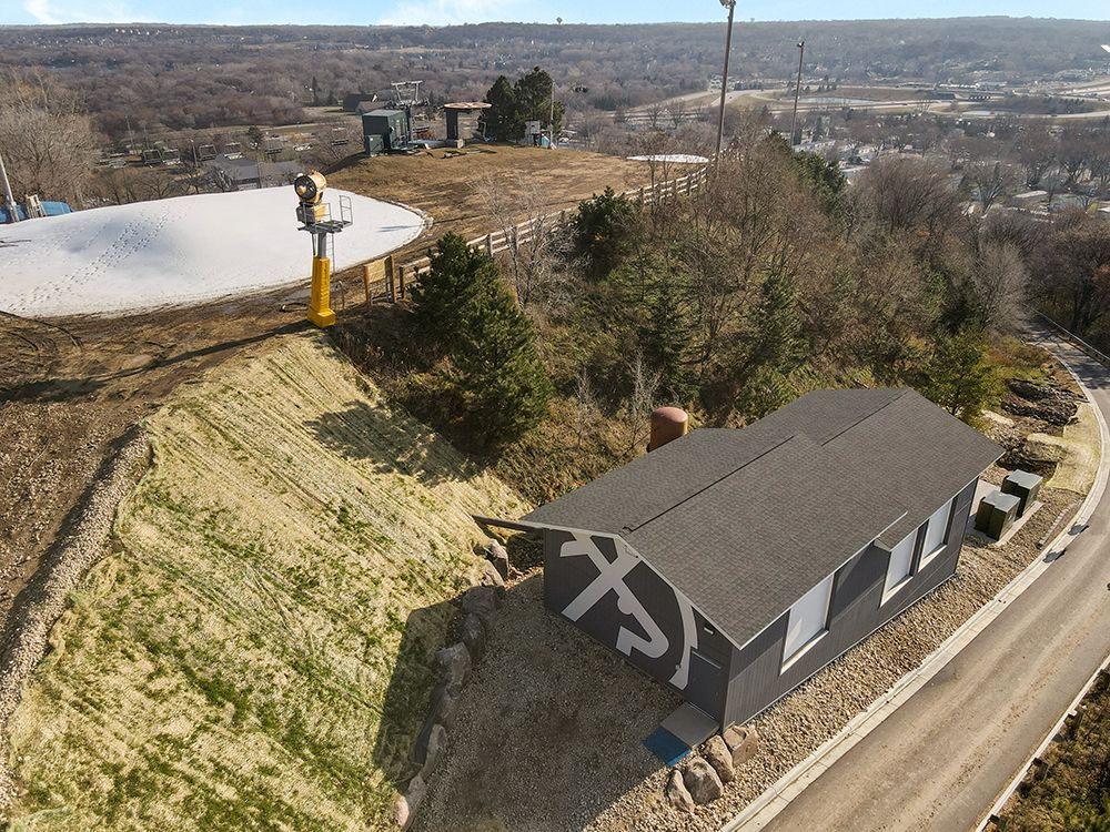 An aerial view of a house on a hill with a ski lift in the background