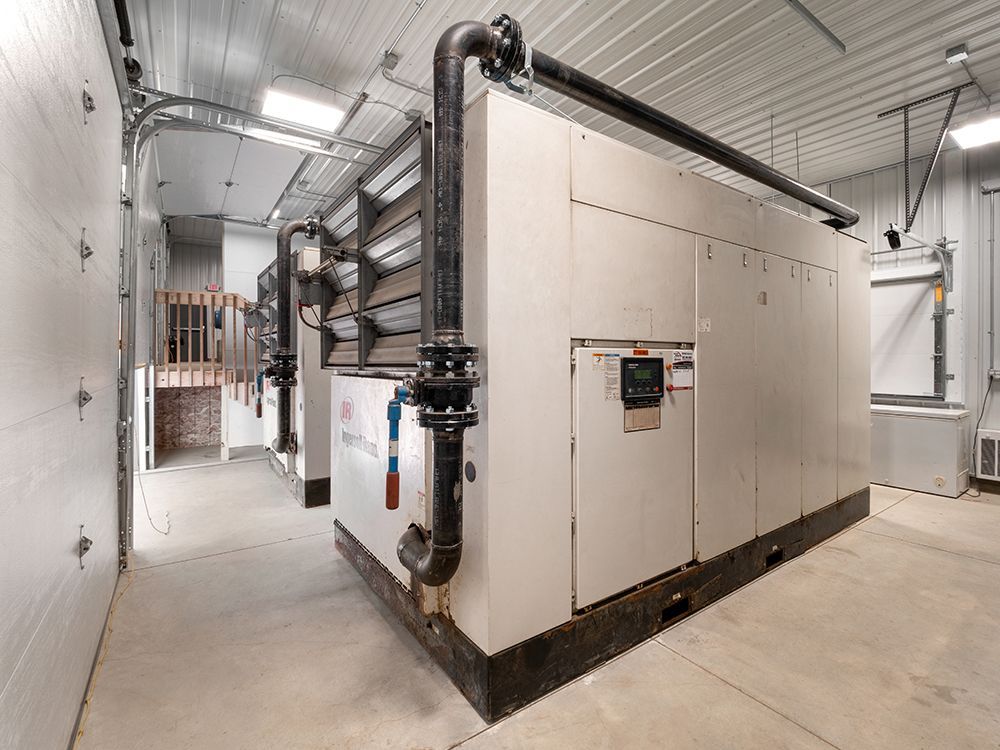 There is a large machine in the middle of a room with pipes coming out of it.