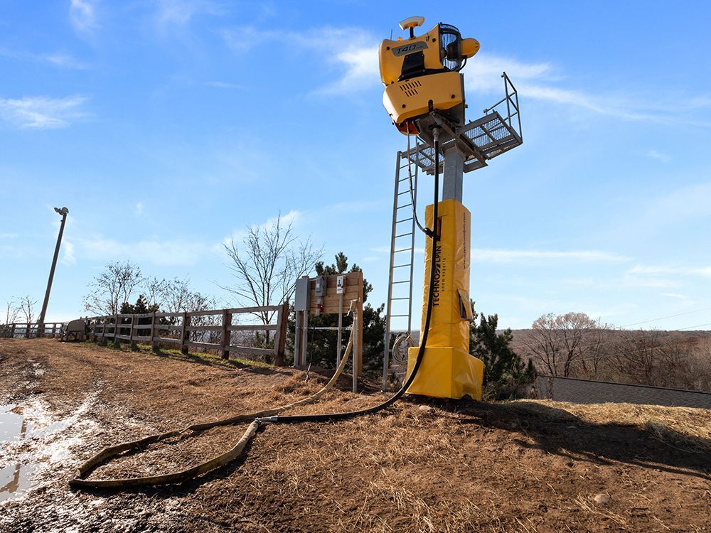 A yellow tower with a ladder attached to it is sitting on top of a dirt hill.