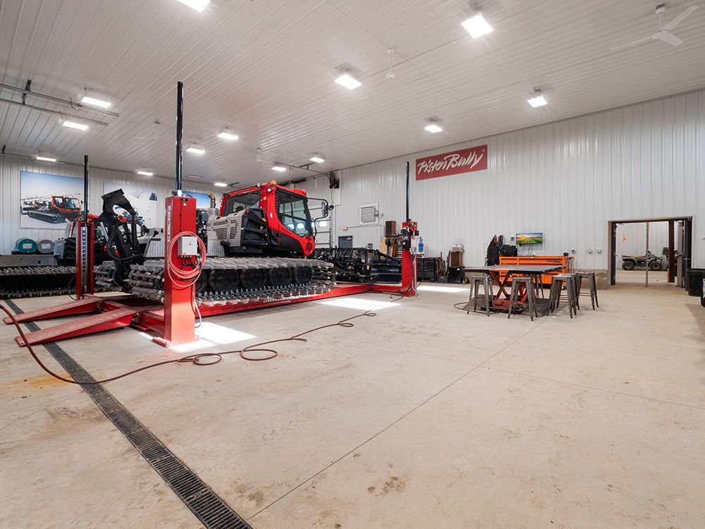 A snowmobile is sitting on a lift in a garage.