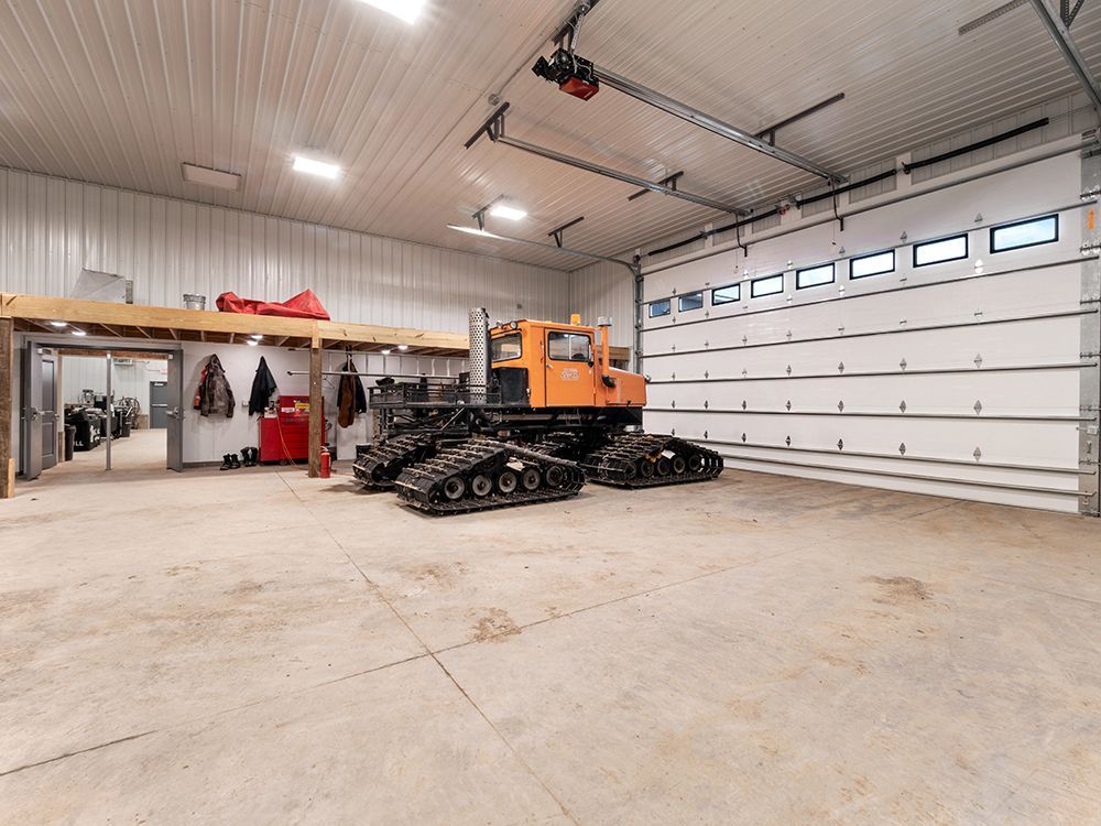 A snowmobile is parked in a garage with a large garage door.