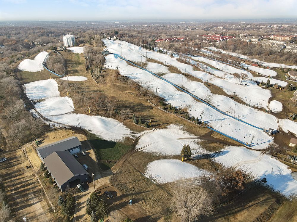 An aerial view of a snow covered golf course with a house in the foreground.