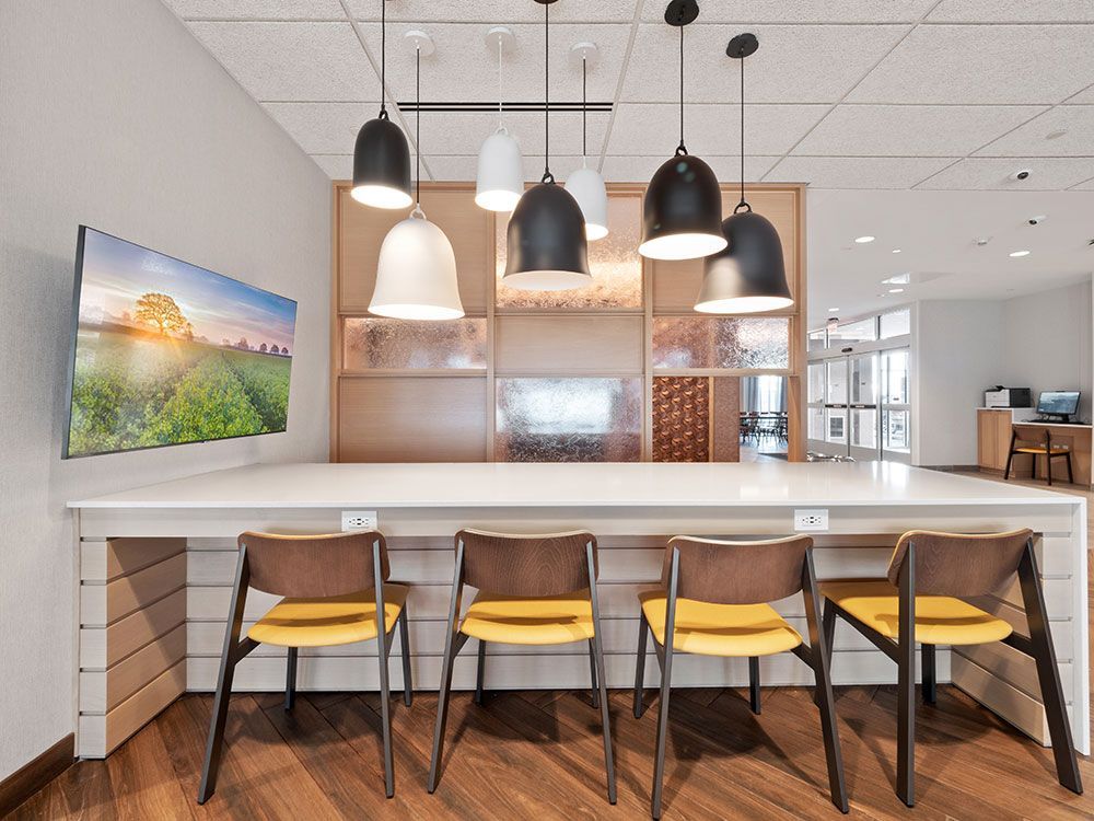 A room with a long table and chairs and a painting on the wall.