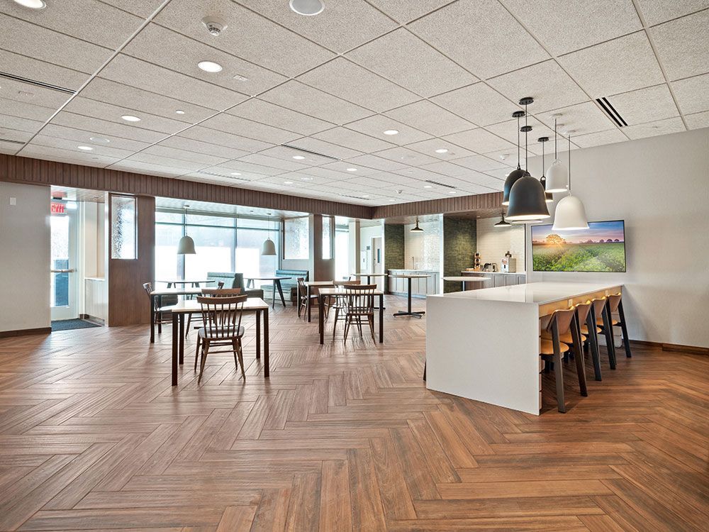 A large room with wooden floors and tables and chairs.