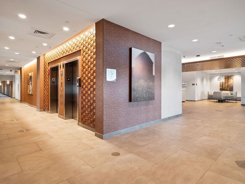 A lobby with two elevators and a painting on the wall.