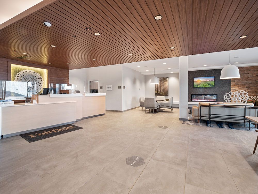A hotel lobby with a white counter and a wooden ceiling.