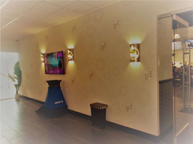 A hallway with a painting on the wall and a trash can.