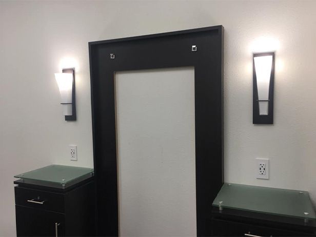 A room with a mirror and two lights on the wall