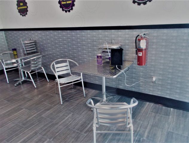 A restaurant with tables and chairs and a fire extinguisher on the wall.